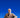 Bearded man sitting on a chair holding a phone against a blue background